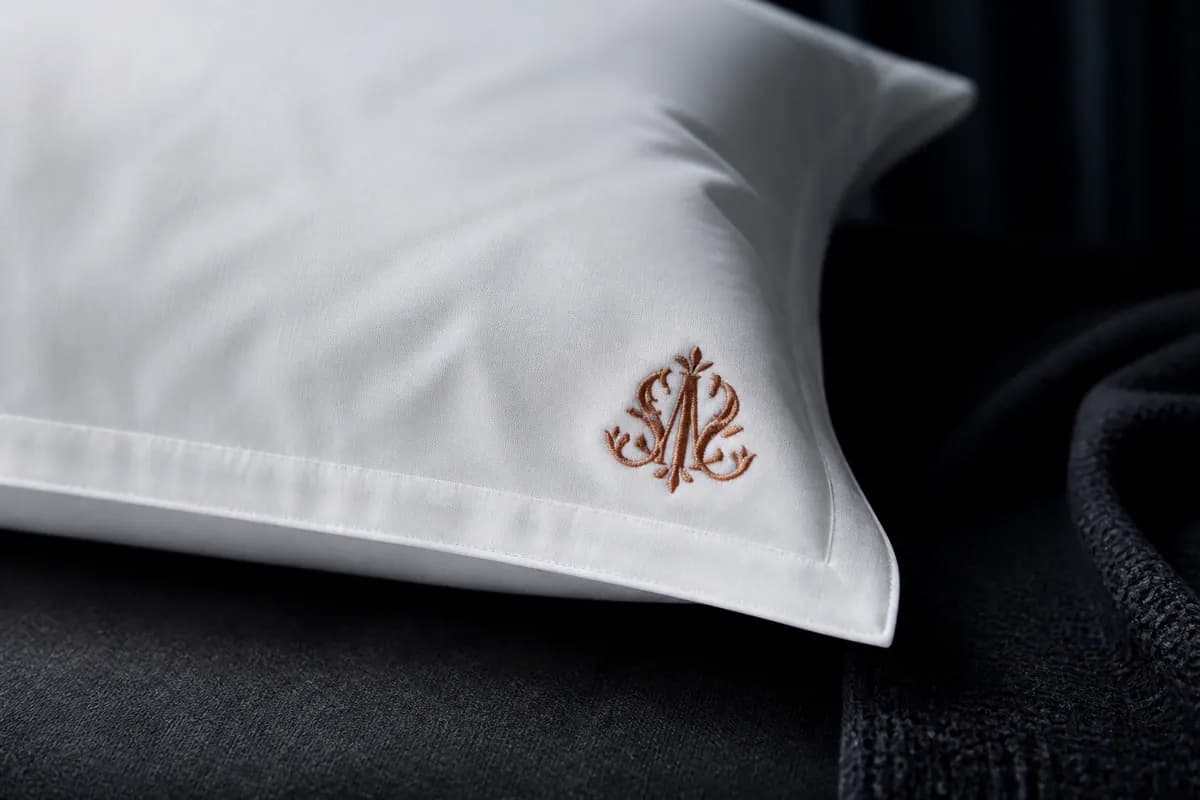 Otel yastık kılıfı köşesinde zarif bakır monogram nakışı